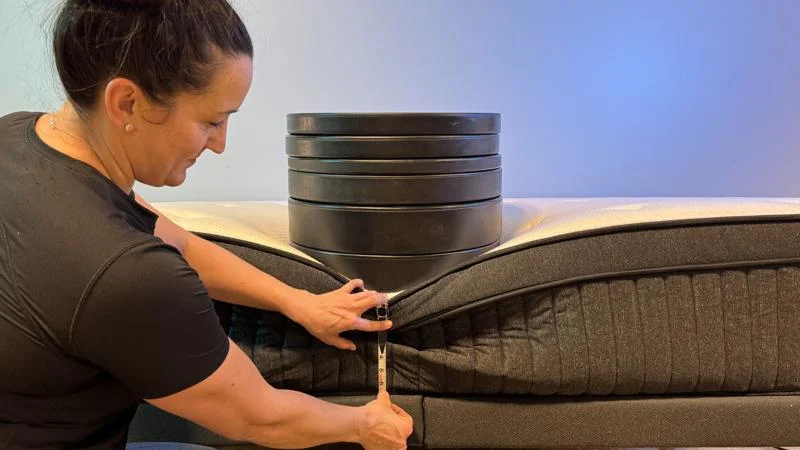 Our tester measures the sinkage from weight plates along the edge of the Titan Plus Luxe Mattress