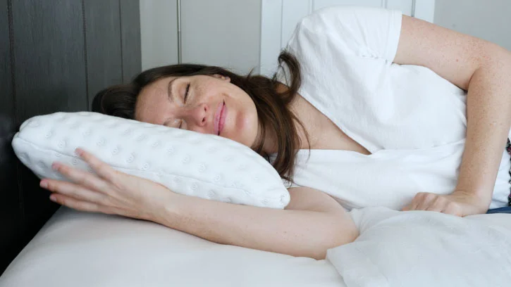 A woman sleeps on her side on the Brooklyn Bedding Talalay Latex pillow. 