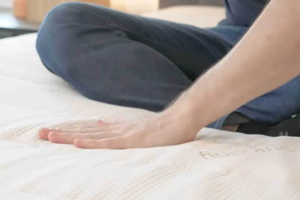 A hand lays over the Zenhaven mattress surface