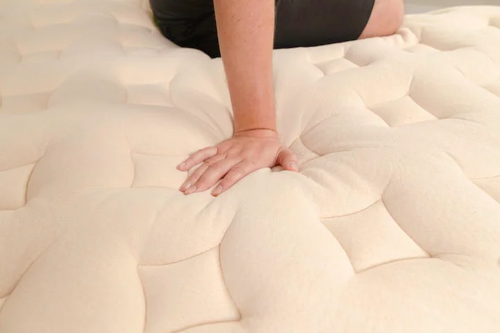 A man presses into the top of the Bear Natural mattress