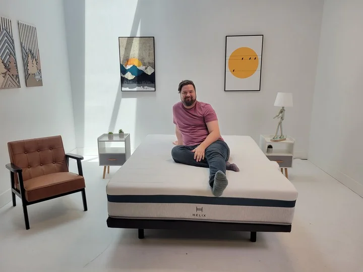 A man sits on top of the Helix Twilight mattress