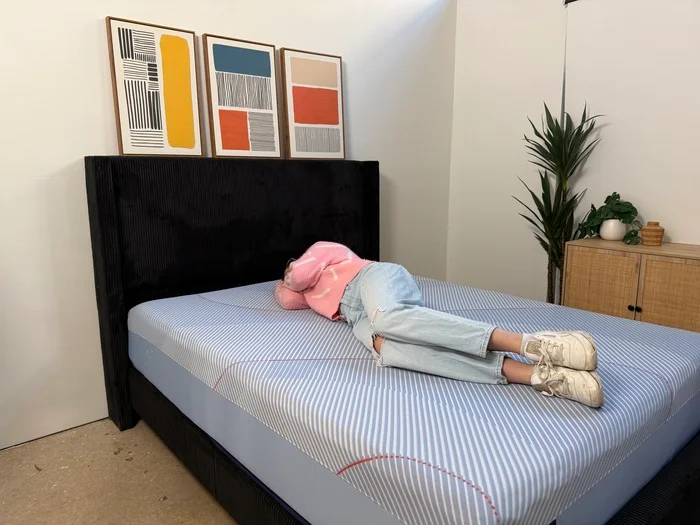 woman in a pink sweater resting on her side on a sealy posturepedic hybrid mattress