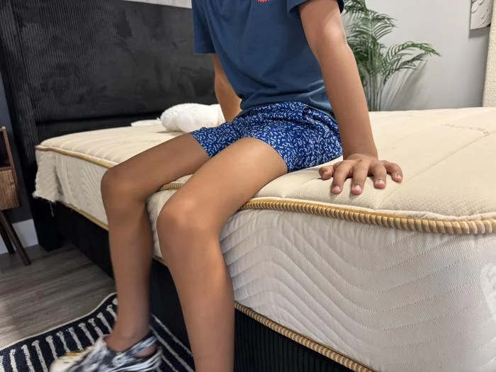 Our tester performs a seated edge support test on a Saatva Youth Mattress