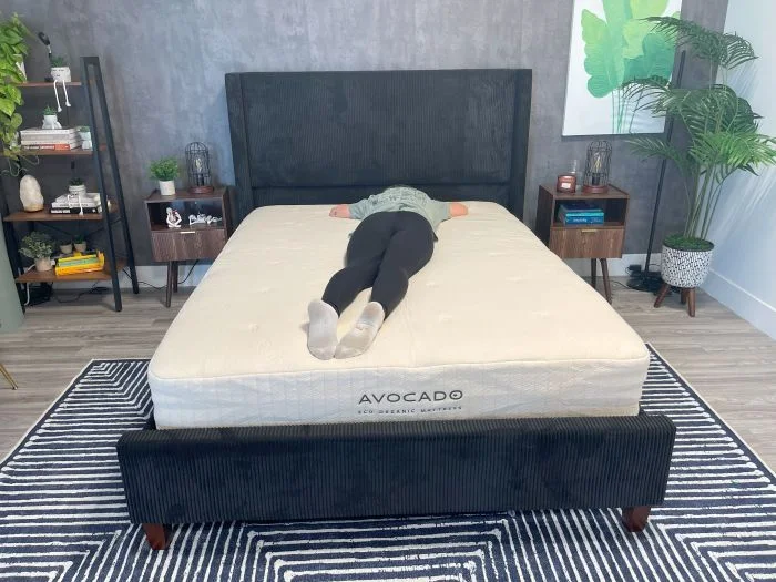 A woman lies on her stomach on the Avocado Eco Organic Mattress