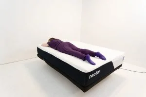 A woman rests on her stomach on the Nectar Classic mattress