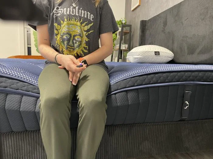 Our tester performs a seated edge support assessment on the DreamCloud Luxe Hybrid