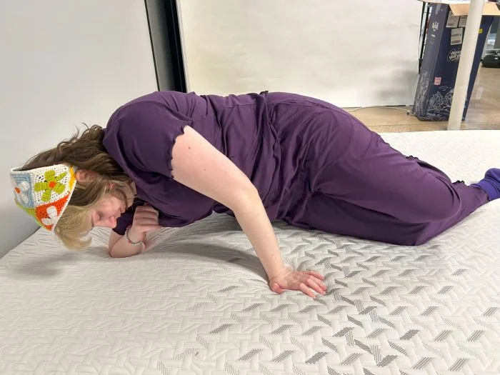 A woman tests switching positions on the Nectar Classic Hybrid mattress.