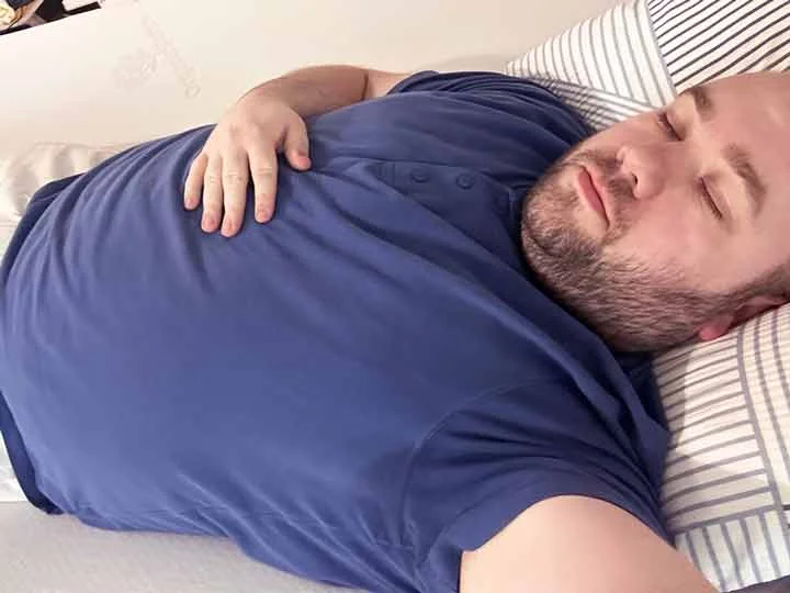 A man sleeps on his back while on top of the Titanflex Mattress topper.