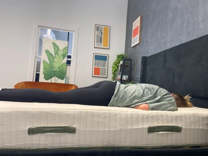 A woman lies on her back on the Avocado Eco Organic Mattress