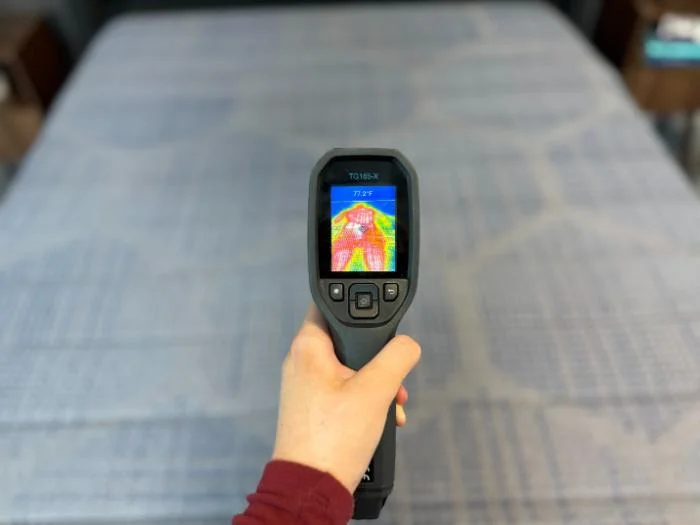 Our tester getting a reading on the mattress temperature after performing our cooling test