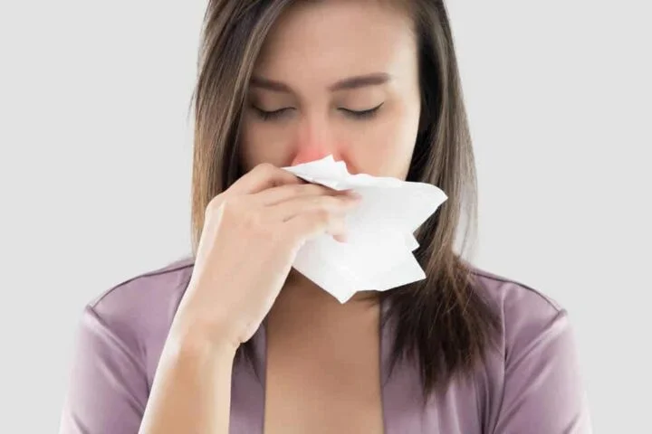A woman blows her nose into a tissue A woman blows her nose into a tissue