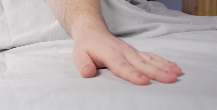 A hand feels a set of soft sheets