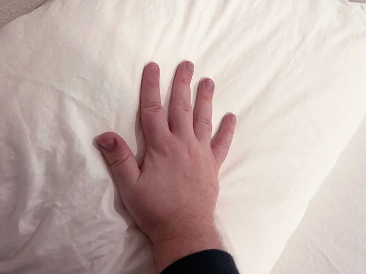 A hand brushes across the Quince Sateen Sheets. A hand brushes across the Quince Sateen Sheets.