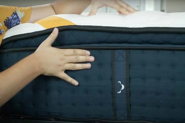 A man shows the side construction of the DreamCloud Premier Rest A man shows the side construction of the DreamCloud Premier Rest