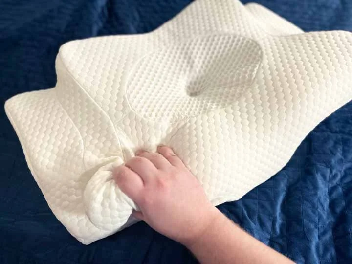 A hand squeezes the Zamat Cervical Butterfly pillow. A hand squeezes the Zamat Cervical Butterfly pillow.
