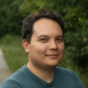 Kenny smiling against a backdrop of trees.