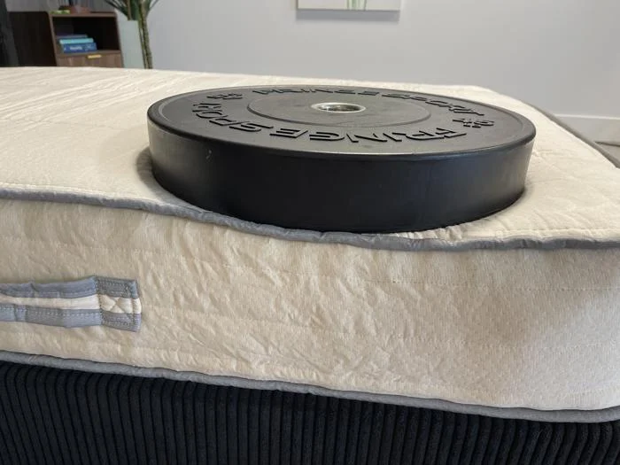 Weight plate on the edge of a Nolah Nurture Kids Mattress