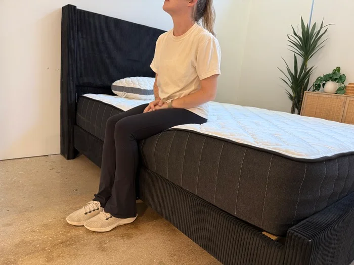 Testing edge support by sitting on the perimeter of the Titan Plus Core mattress