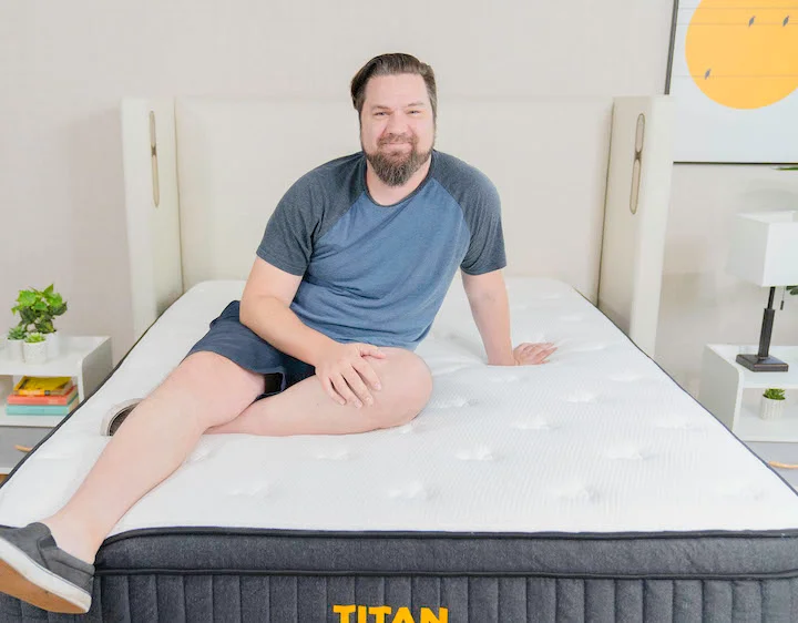 a man sits on top of the Titan Plus mattress