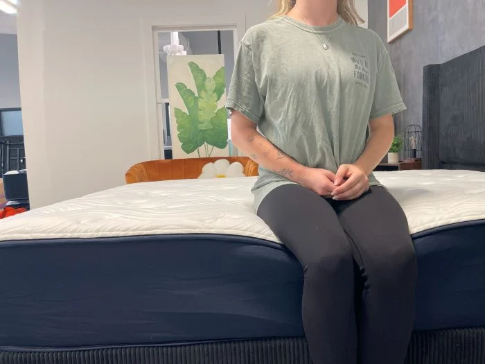 A woman sits on the edge of the Big Fig Classic mattress