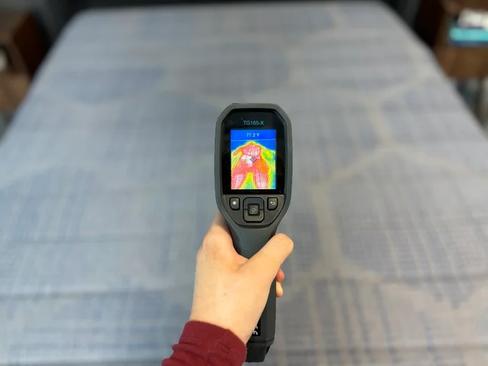 A thermal gun is aimed at the surface of the Copperflex mattress, displaying the thermal outline of someone resting on top of it