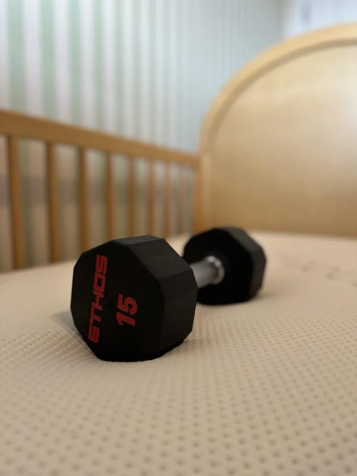 dumbbell resting on the saatva crib mattress