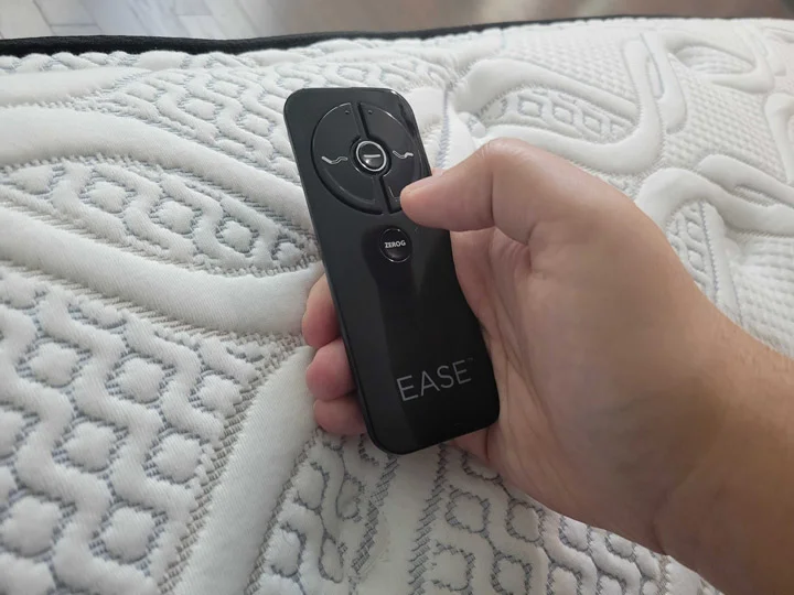 A man holds the Sealy Ease remote in his hand