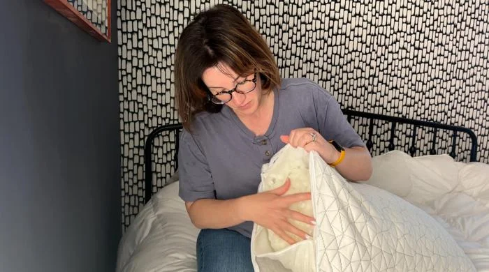 Our tester adjusting the fill inside a Coop Sleep Goods Original Adjustable Pillow
