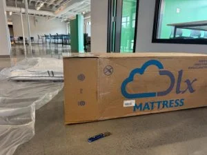 The DLX Classic Two-Sided Mattress flat and still in plastic, pictured with its box