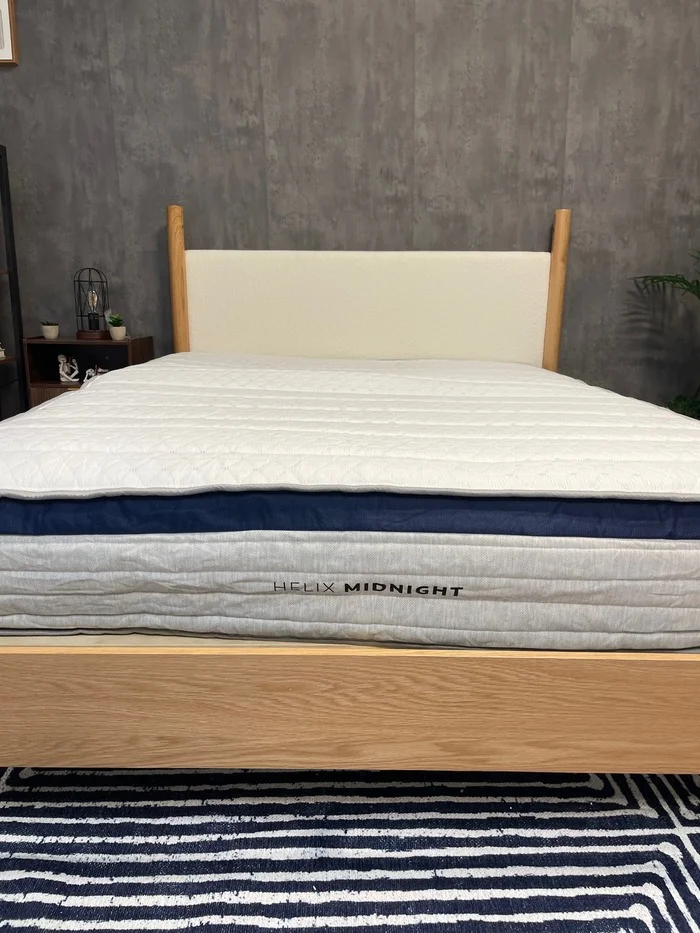 The Helix Midnight mattress on a light wood frame, not yet fully expanded