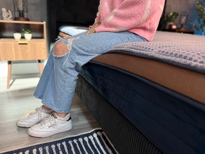 A tester sits on the edge of the Copperflex mattress