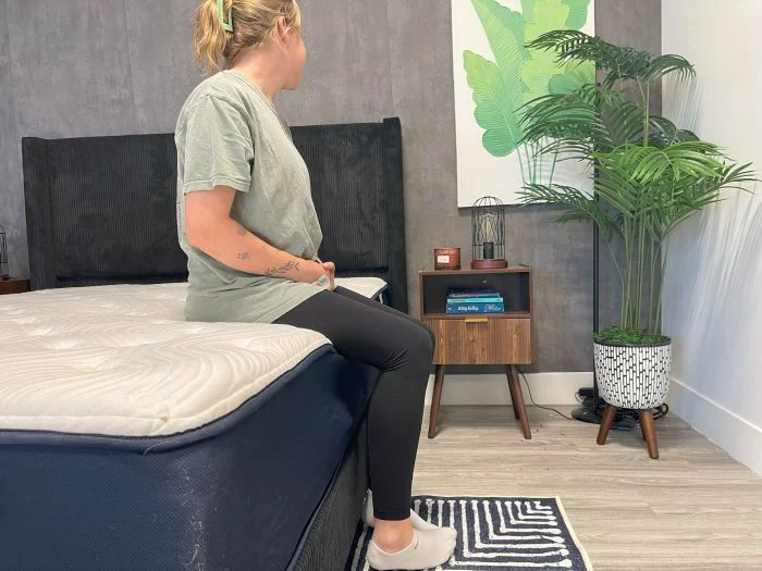A woman sits on the edge of the Big Fig Classic mattress