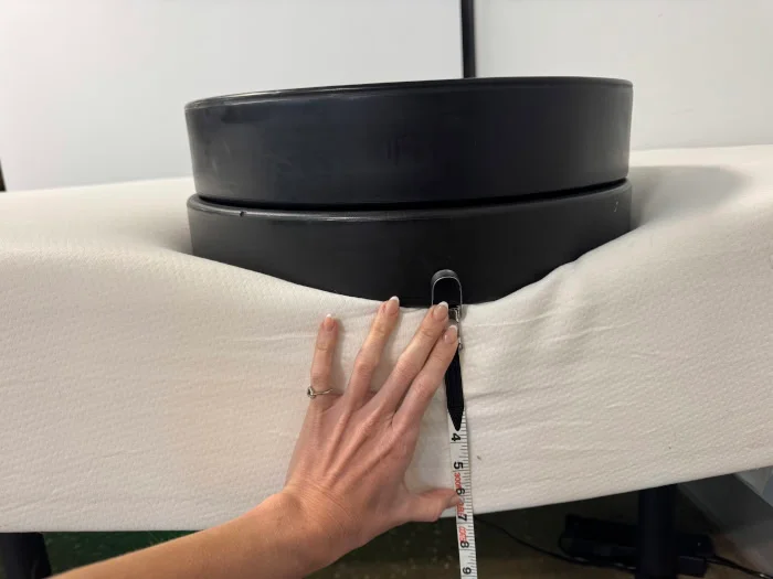 Our tester measuring weight plates on the edge of a Polysleep Sierra Mattress