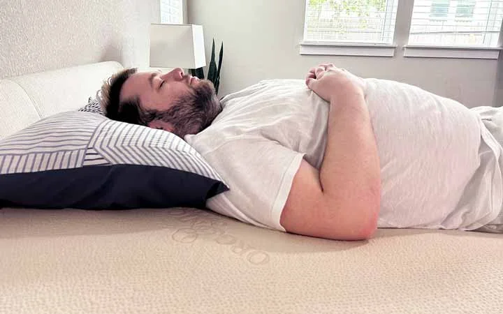 A man rests on his back on top of the Plushbeds Latex topper. A man rests on his back on top of the Plushbeds Latex topper.