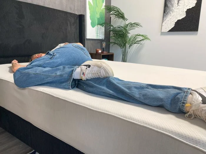 A woman sleeps on her side on the Boring AF mattress