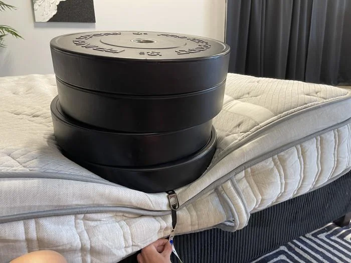 Measuring weight plates on the edge of the Leesa Plus Hybrid Mattress
