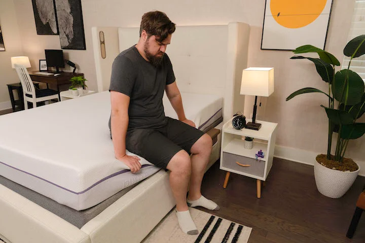a man sits on the side of the Purple Original mattress