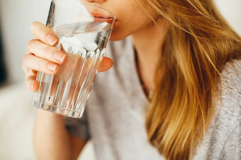 Hydration and Sleep: Is It Good to Drink Water Before Bed? a woman drinks a glass of water