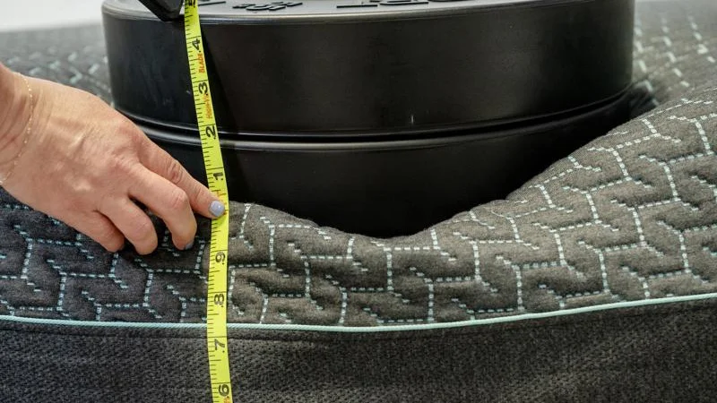 Our tester measures the sinkage from weight plates along the edge of the Tuft & Needle Mint Hybrid Mattress