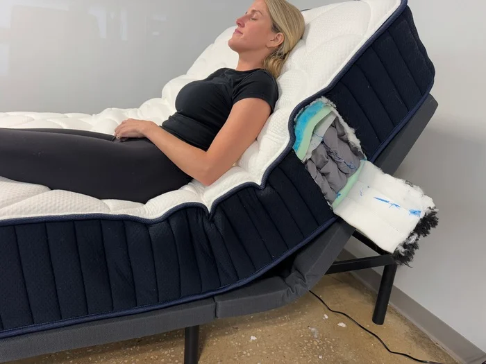 Woman resting on the DreamCloud Classic Hybrid with the head of the mattress elevated by an adjustable base