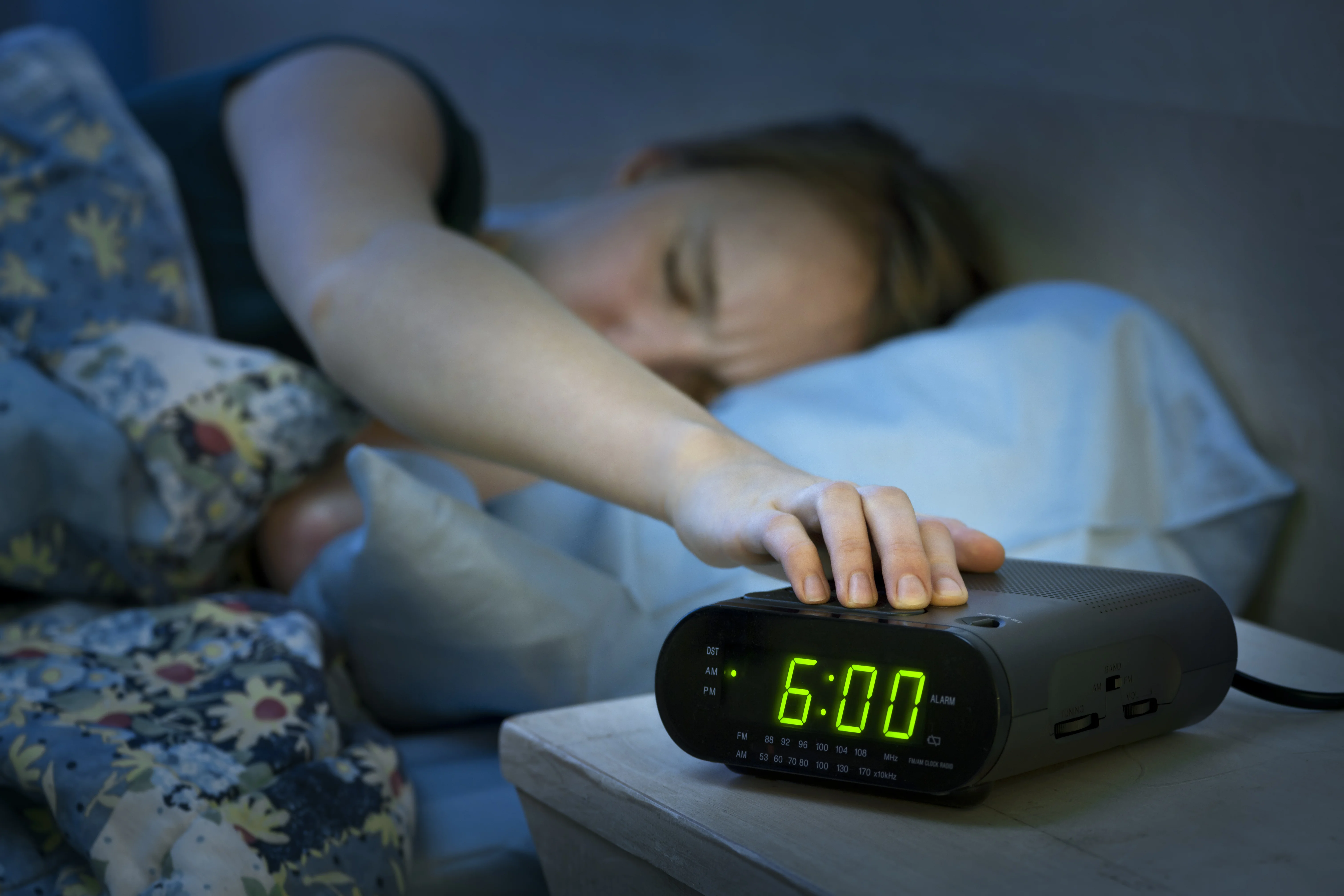 tired woman hitting alarm clock