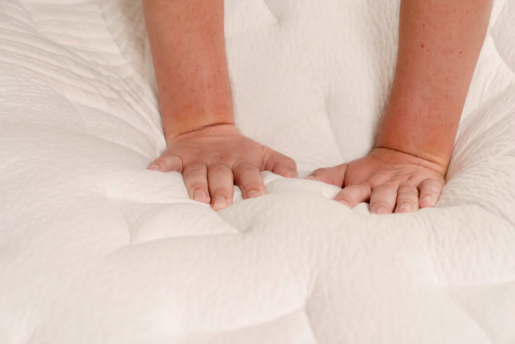 a man presses into the cover of the Nolah Evolution Comfort + mattress