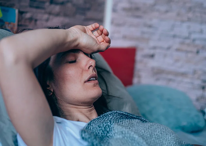 A woman sleeps on her back with a fever