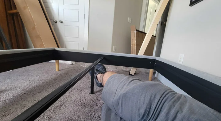 A shot of a man resting while building the Nectar Claremont bed frame