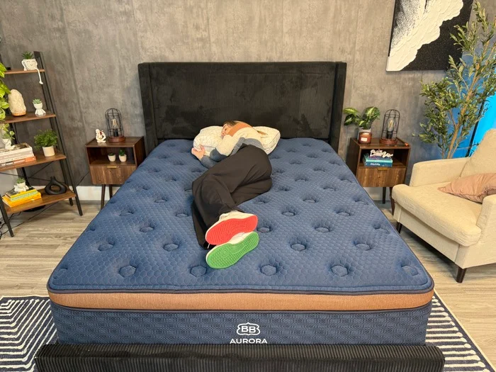 A woman lies on her side on the Aurora Luxe mattress