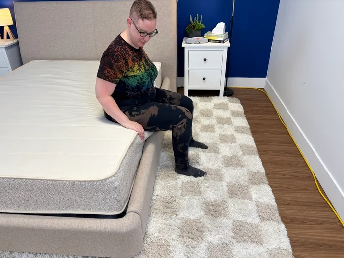 tester seated on the edge of the birch natural mattress to test edge support