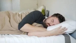 A man sleeps on his side using the SoftHeat Luxury Fleece Heated Blanket.