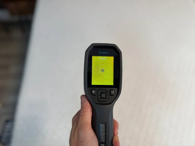 A temperature gun pointed at the surface of the Tuft & Needle Original mattress, displaying a reading of 72.5 degrees