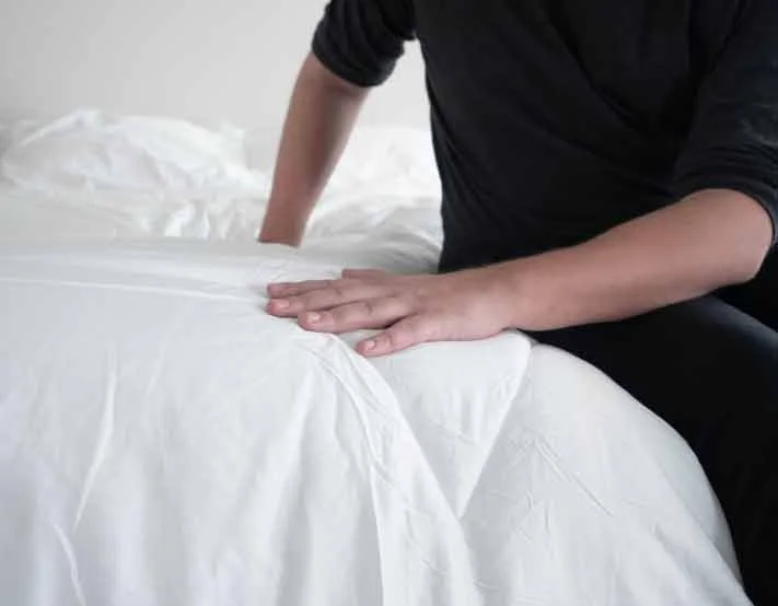 A man feels the top of a comforter. A man feels the top of a comforter.