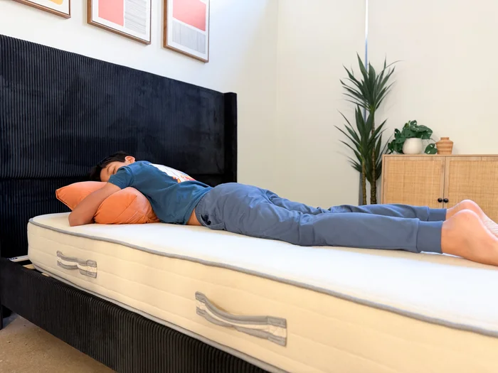A young tester rests on his stomach on top of the Nolah Nurture kids mattress